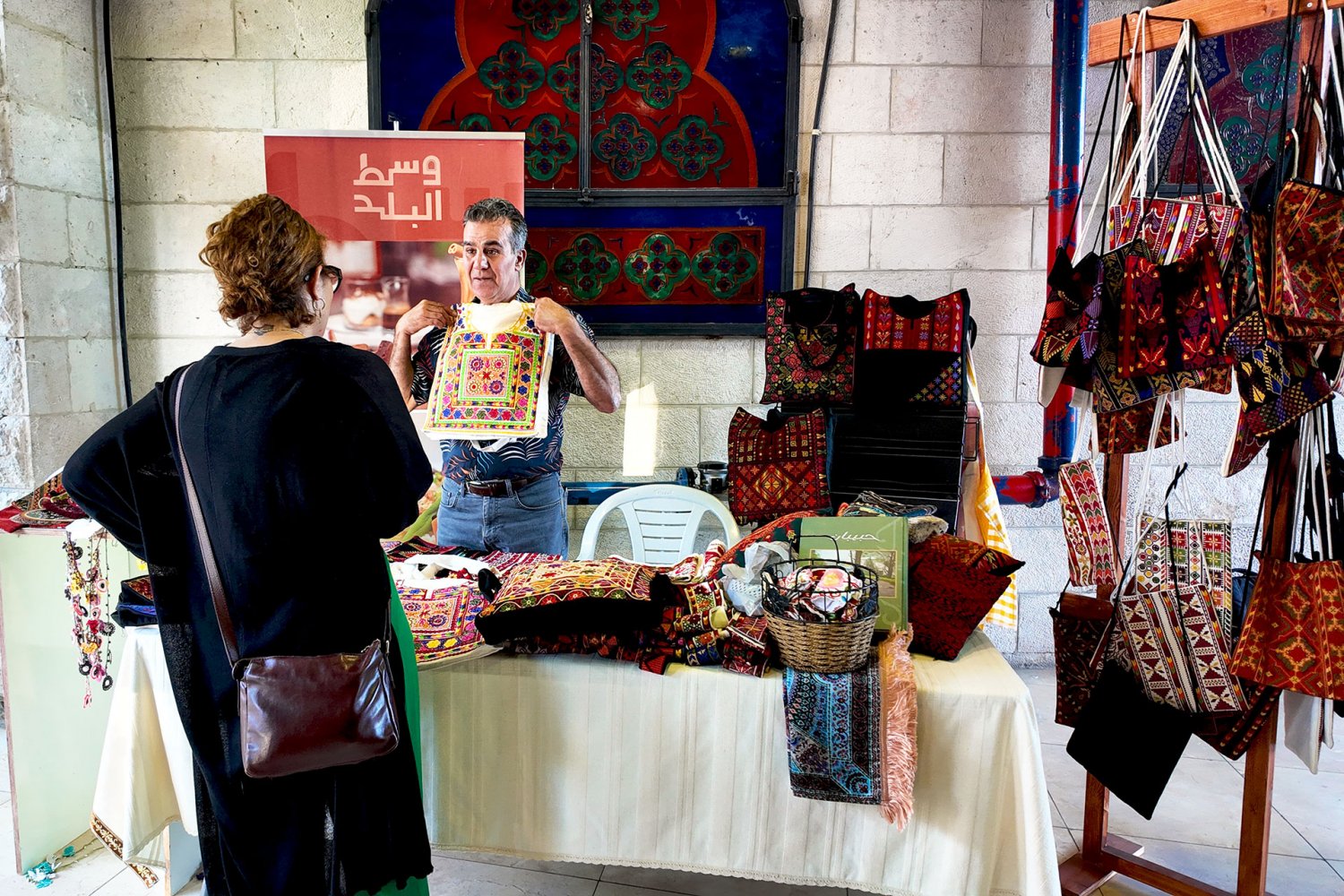 Issa Qawasmi displays his locally made pillowcases at the Yabous Cultural Centre bazaar, Jerusalem, August 17, 2024.