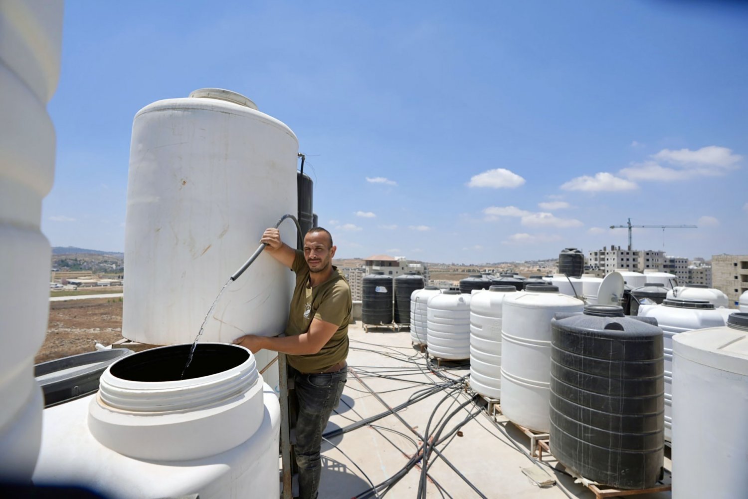 A Kufr ‘Aqab resident fills a rooftop tank amid a severe water shortage, July 29, 2024