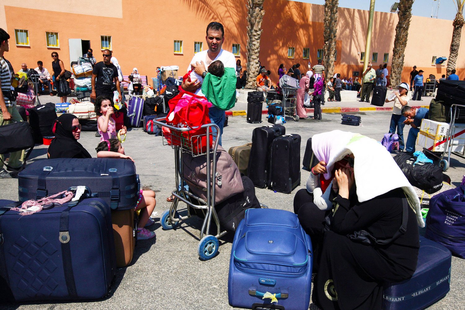 Palestinians and foreigners wait under scorching sun at the Allenby Bridge Crossing terminal, between Jordan and the West Bank, July 28, 2009.