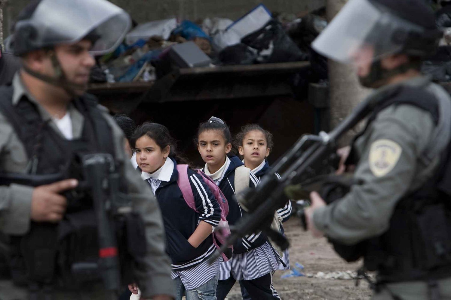 Palestinian schoolgirls pass Israeli border police, Shu‘fat refugee camp, February 8, 2010.