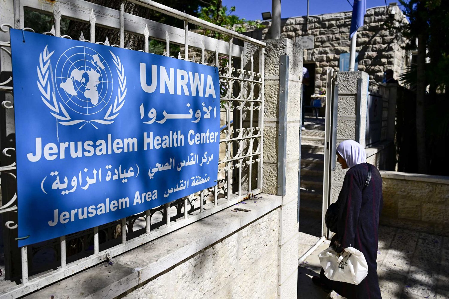 Woman stands in front of the UNRWA health clinic in East Jerusalem.