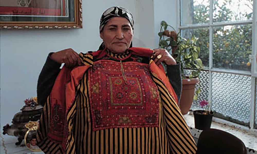 Sarah Odeh displays her Palestinian embroidered dress in 1999