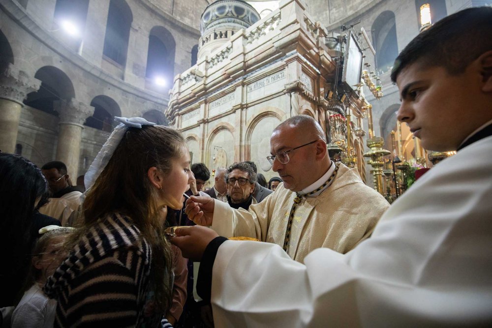 A Catholic priest administers holy communion at the Church of the Holy Sepulchre, Easter 2024.