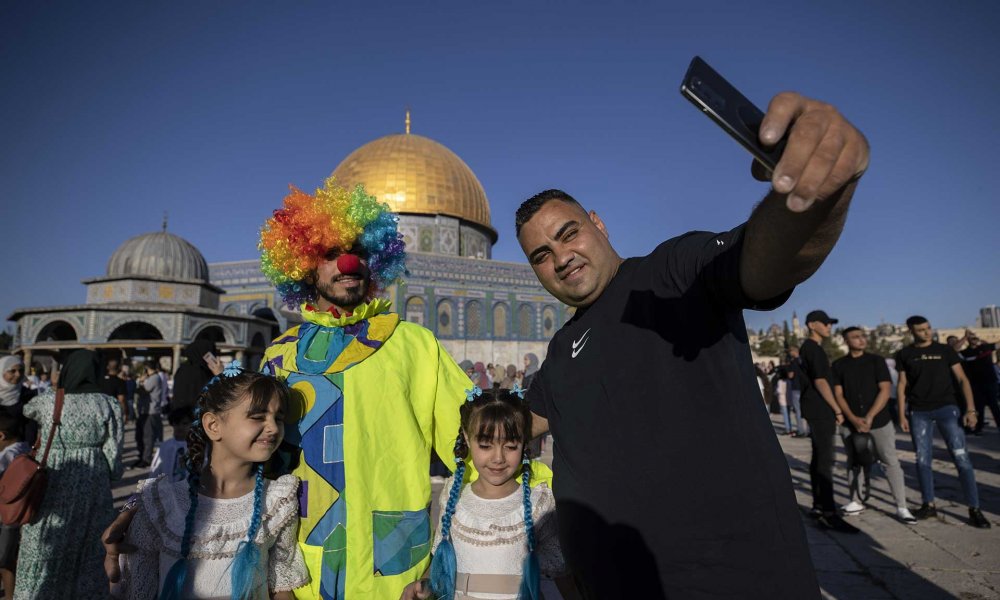 A Palestinian Muslim family takes a selfie with a clown during Eid al-Adha in Jerusalem, 2022.