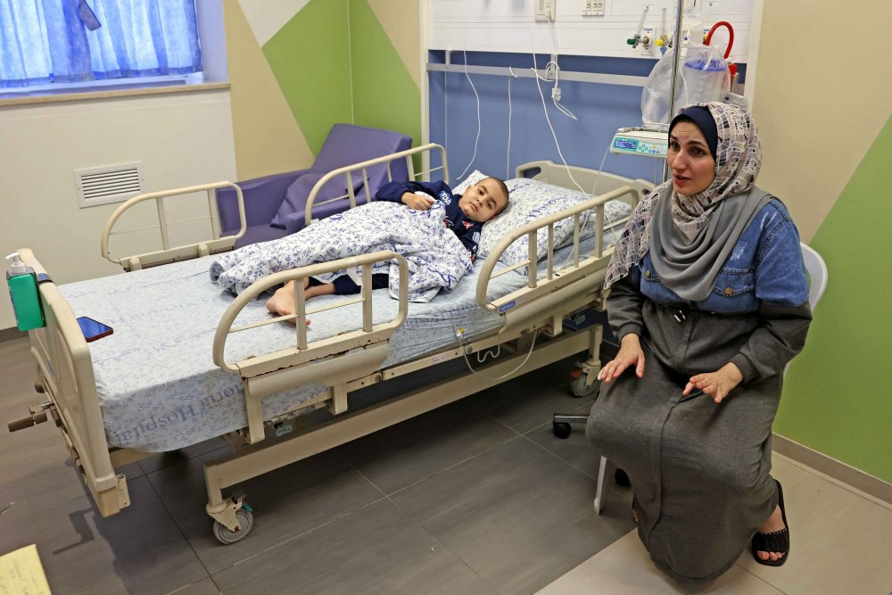 Palestinian mother from Gaza sits by her young son’s hospital bed in East Jerusalem, October 17, 2023.