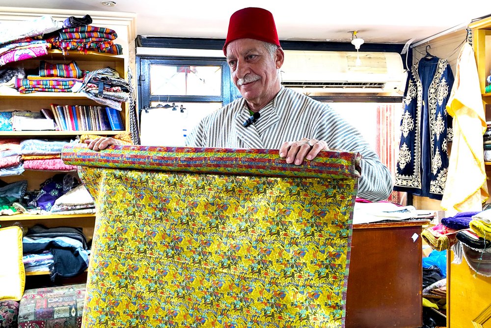 Bilal Abu Khalaf shows special fabrics with interwoven gold at his shop, Jerusalem, July 22, 2024.