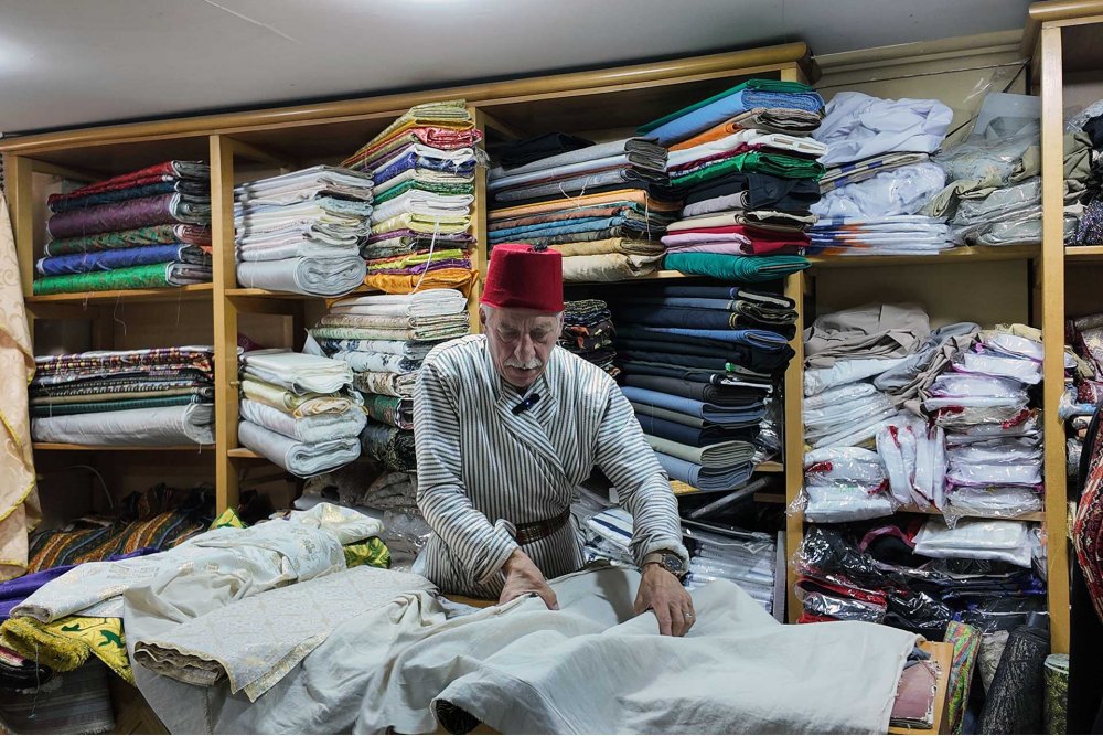 Bilal Abu Khalaf organizes fabrics at his shop in Jerusalem’s Old City, July 22, 2024.