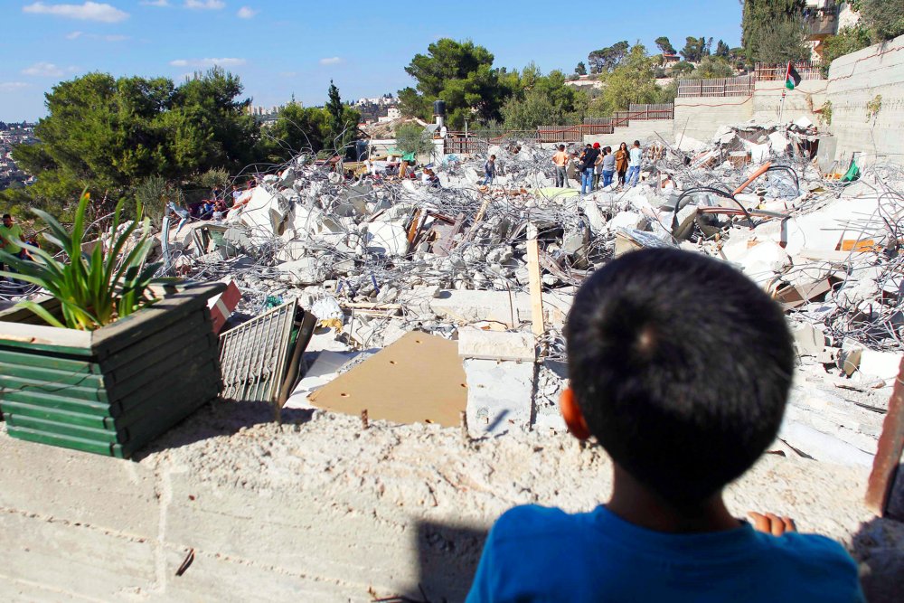 Palestinians walk on the debris of buildings after Israel demolished them, East Jerusalem, September 2016.