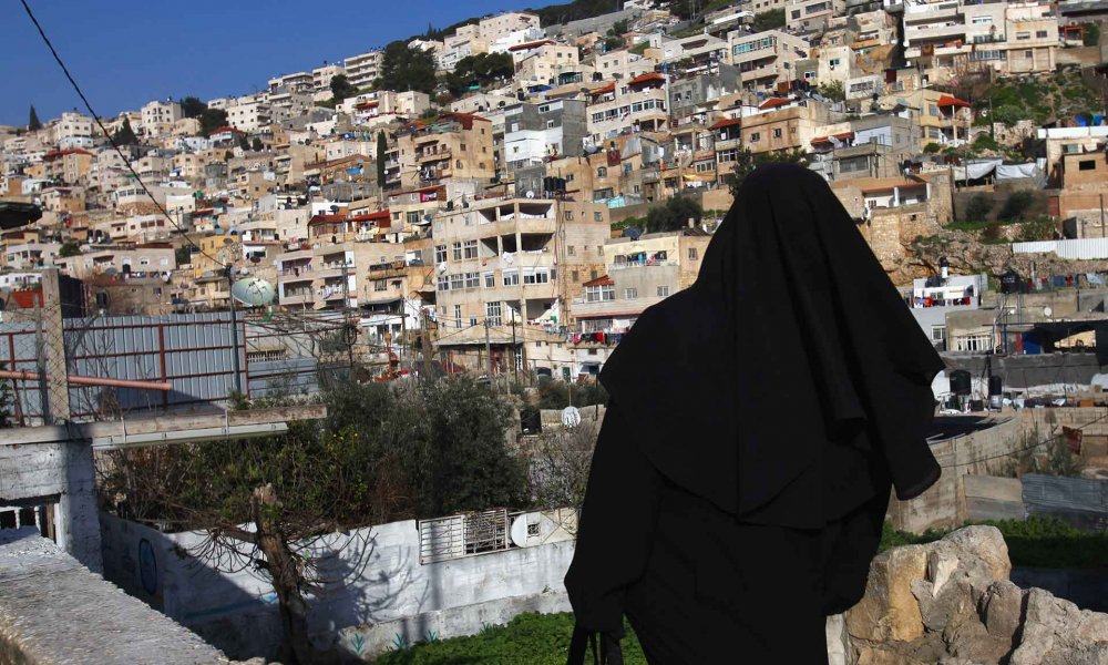 Palestinian woman in al-Bustan, Silwan, East Jerusalem, with homes of Palestinians in the background, March 2, 2010