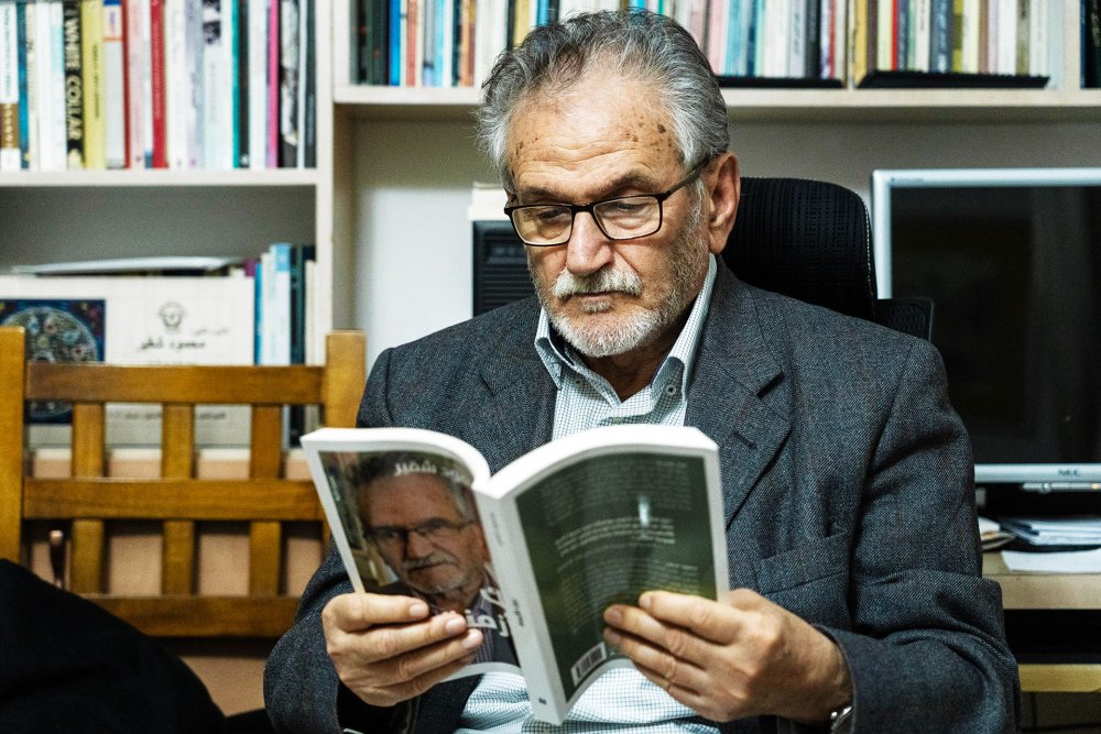 Jerusalem author Mahmoud Shukair in his library, reading one of his books