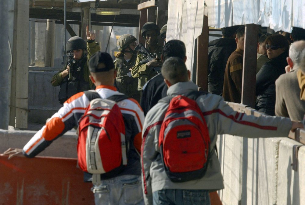 Two Palestinian schoolboys wait for Israeli soldiers to allow them to pass the Qalandiya checkpoint so they can get to school, December 13, 2005.