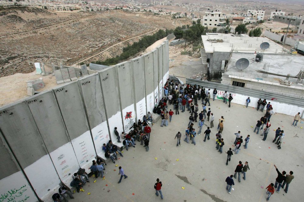 Palestinian schoolboys play by Israel’s Separation Wall in their schoolyard in ‘Anata, on the outskirts of Jerusalem, December 12, 2005. 