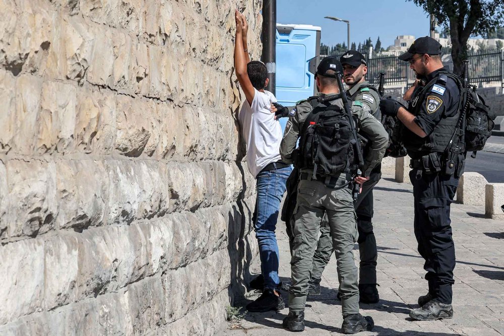 Israeli police search a Palestinian youth outside the Old City of Jerusalem, October 13, 2023.