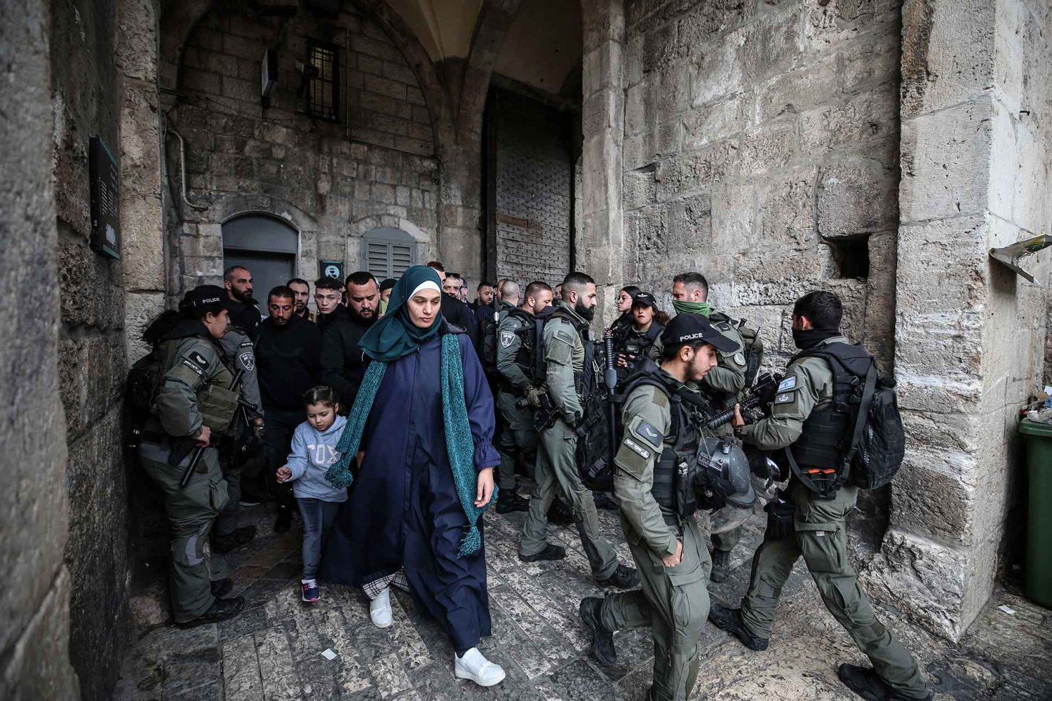 A Palestinian woman and child pass through a crowd of Israeli police during Ramadan in Jerusalem’s Old City, March 15, 2024.