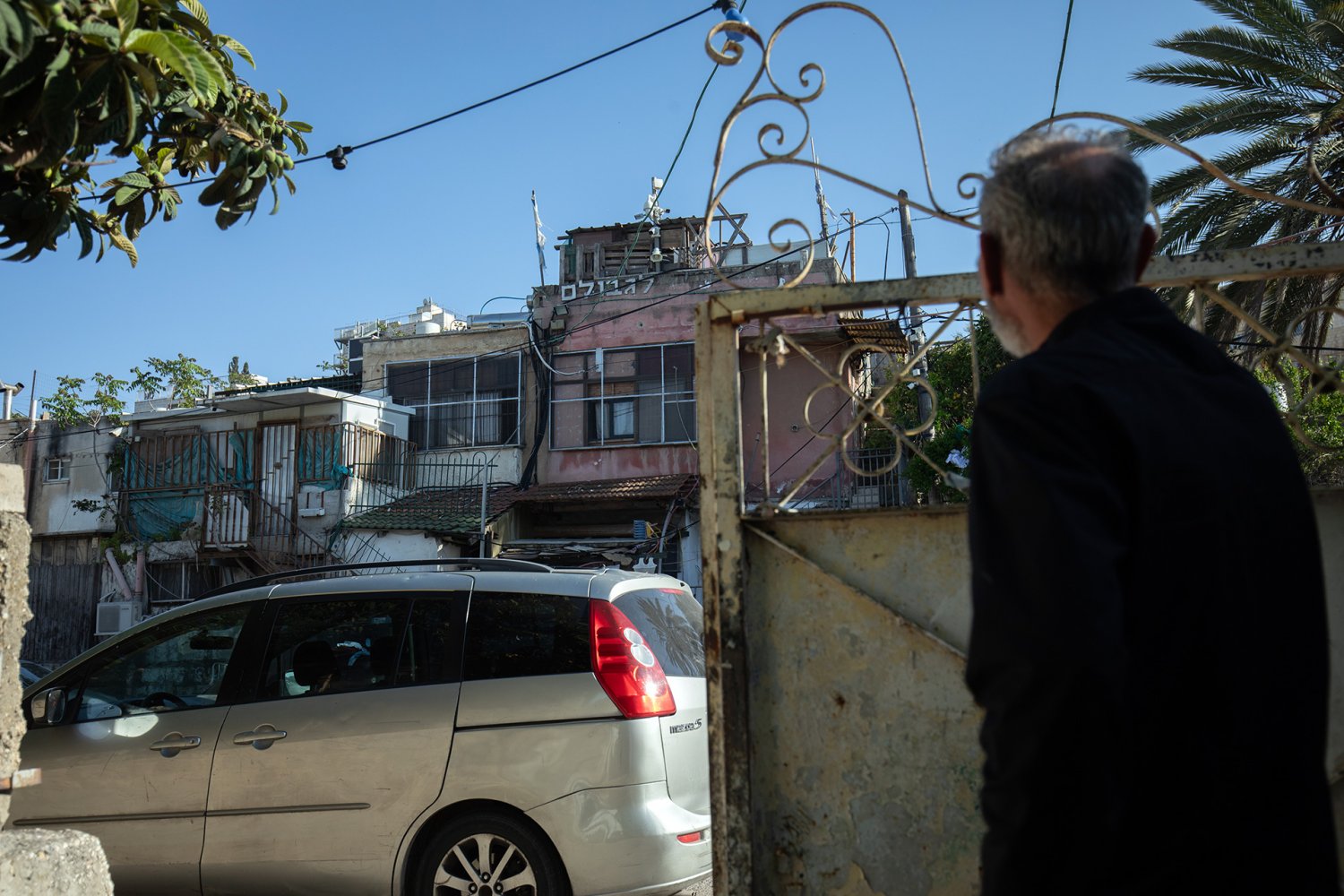 Saleh Diab of Sheikh Jarrah stands at his gate and looks at the house across the street that Jewish settlers seized in 2009