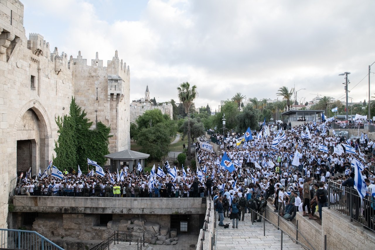 Israelis wave flags as they walk across the closed Palestinian Damascus Gate plaza during the Jerusalem Day flag march, May 18, 2023.