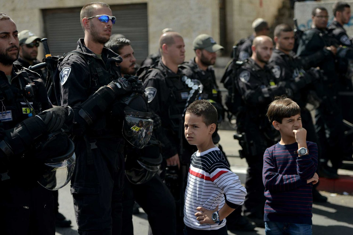 Palestinian children stand by massed Israeli police in Jerusalem, October 10, 2014